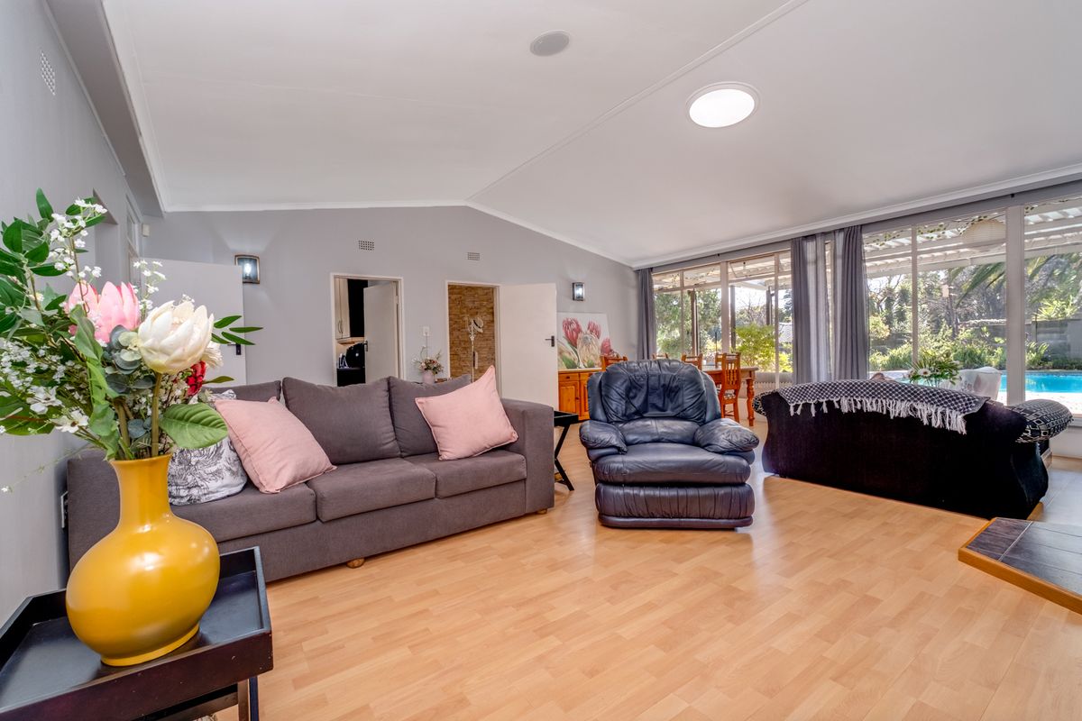 Spacious living room featuring laminate flooring, recessed lighting, a skylight, and large sliding glass doors providing natural light and access to the outdoor area.
