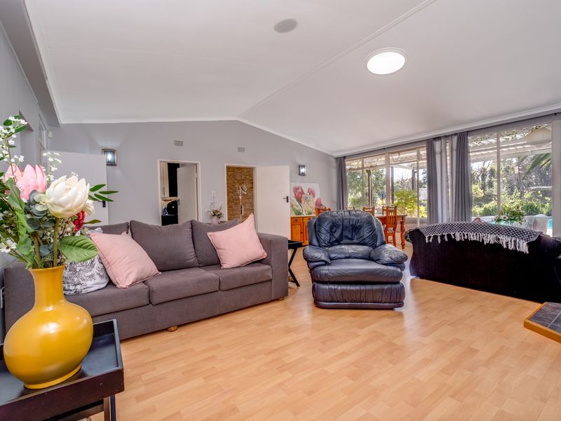 Spacious living room featuring laminate flooring, recessed lighting, a skylight, and large sliding glass doors providing natural light and access to the outdoor area.