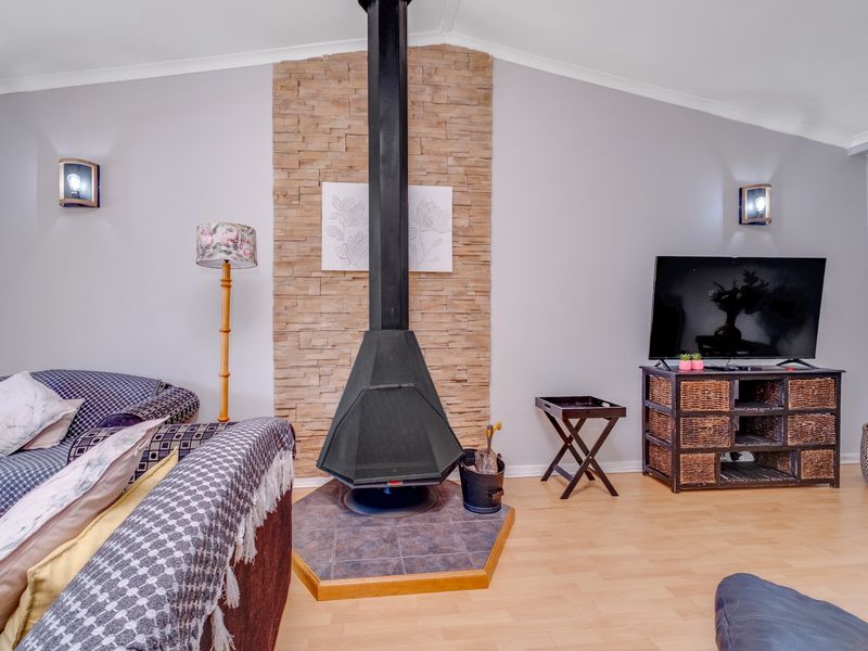 Living room featuring a central freestanding fireplace with a stone feature wall and light-toned laminate flooring.