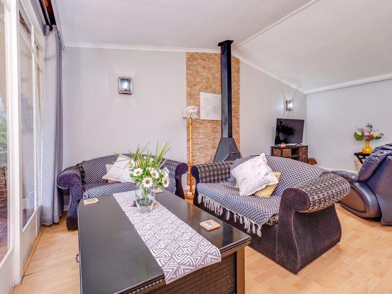 A comfortable living room featuring a stone-clad fireplace, laminate flooring, and large sliding glass doors that provide access to the outdoor area.