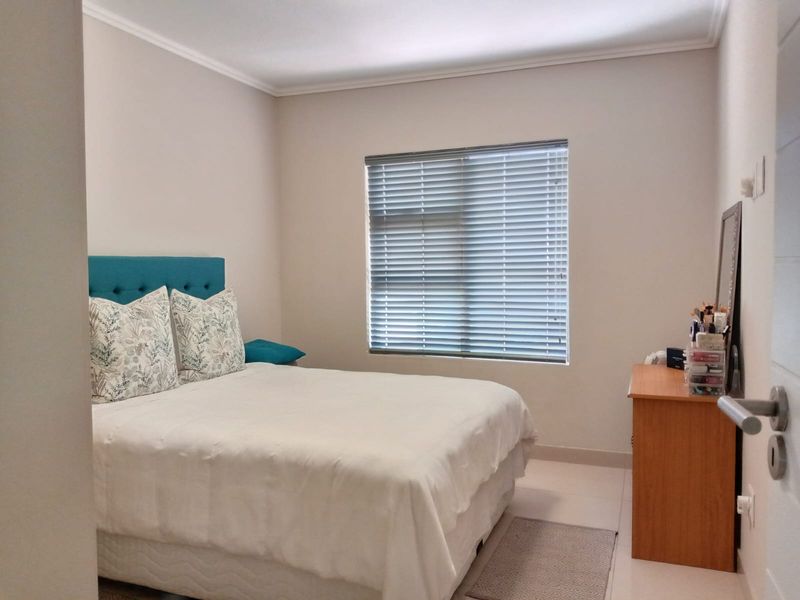A well-maintained bedroom featuring neutral walls, tiled flooring, and venetian blinds, offering a clean and functional living space.