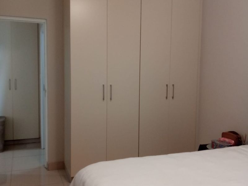 A bedroom featuring neutral-toned built-in cupboards, tiled flooring, and clean finishes, providing ample storage space.