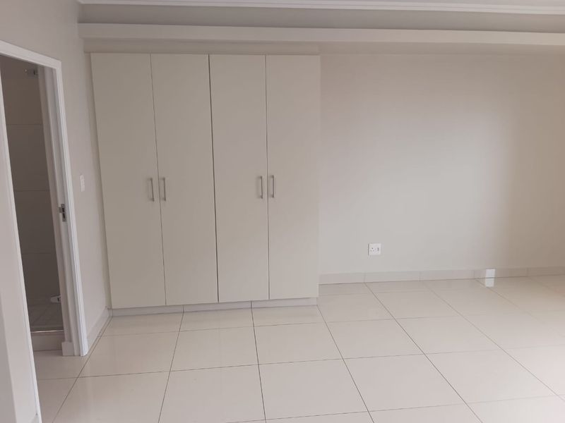 A clean, empty bedroom featuring neutral tiled flooring and modern built-in cupboards, offering a blank canvas for personalization.