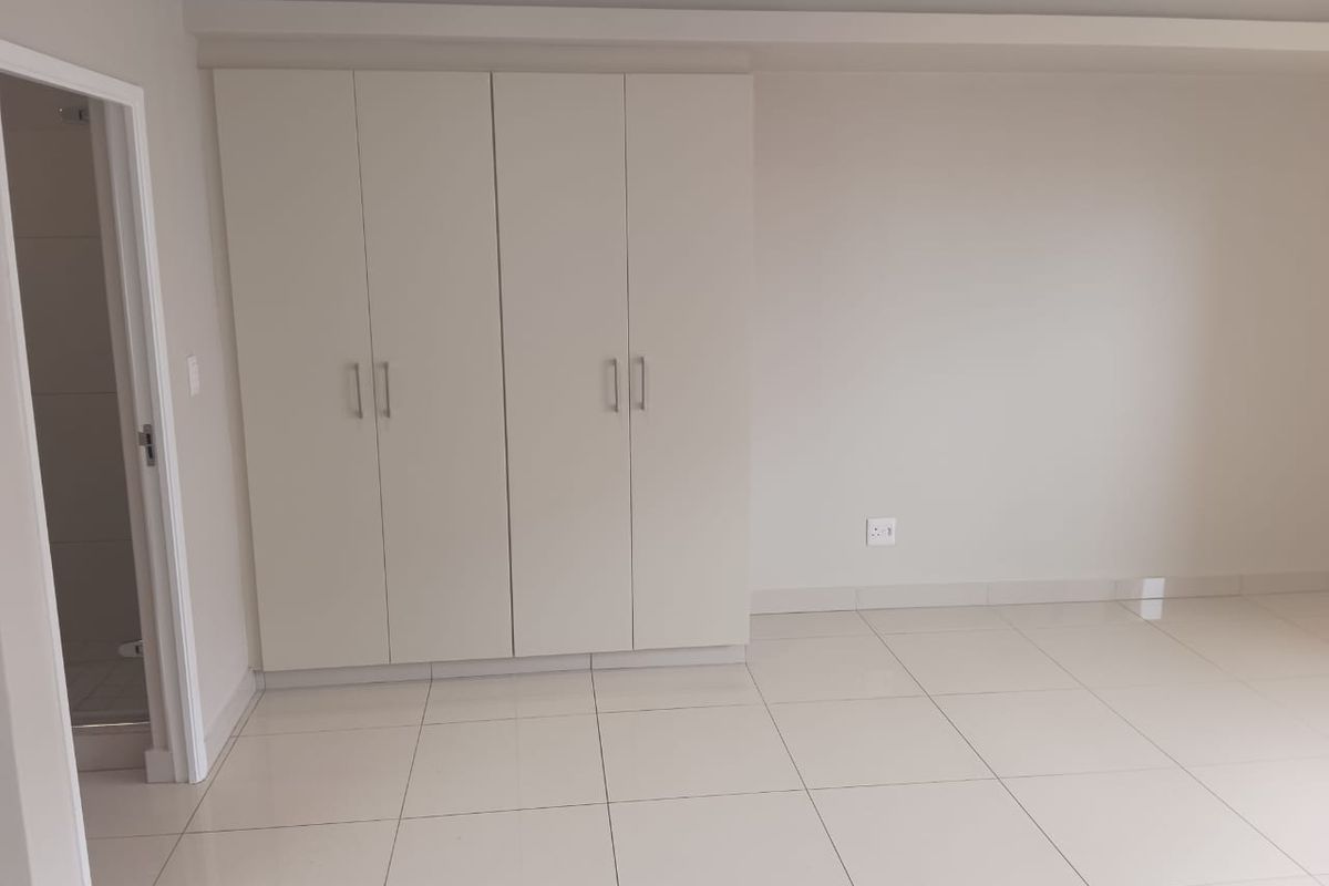 A clean, empty bedroom featuring neutral tiled flooring and modern built-in cupboards, offering a blank canvas for personalization.
