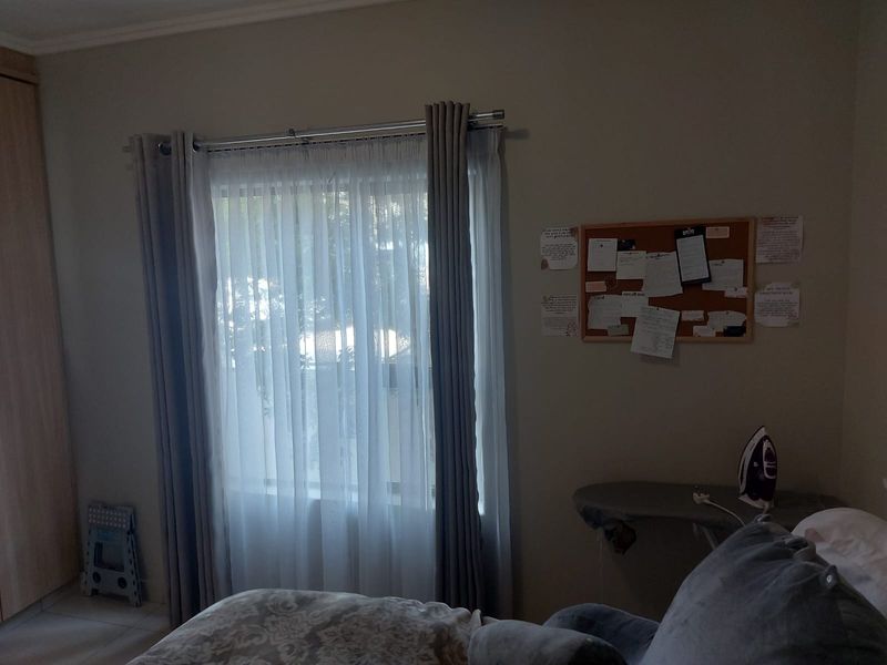 A bedroom featuring a built-in wardrobe and a window with installed curtain rods, providing a functional and neutral living space.