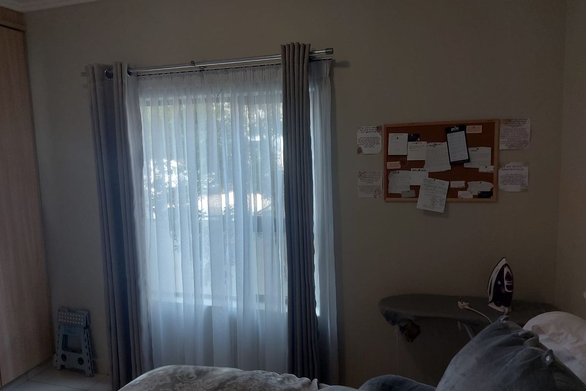 A bedroom featuring a built-in wardrobe and a window with installed curtain rods, providing a functional and neutral living space.