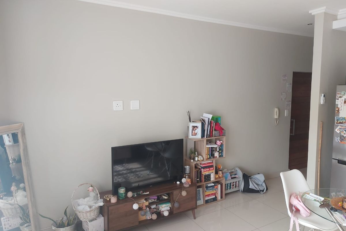 A bright living area featuring neutral walls, tiled flooring, and an integrated intercom system, providing a clean and functional space.