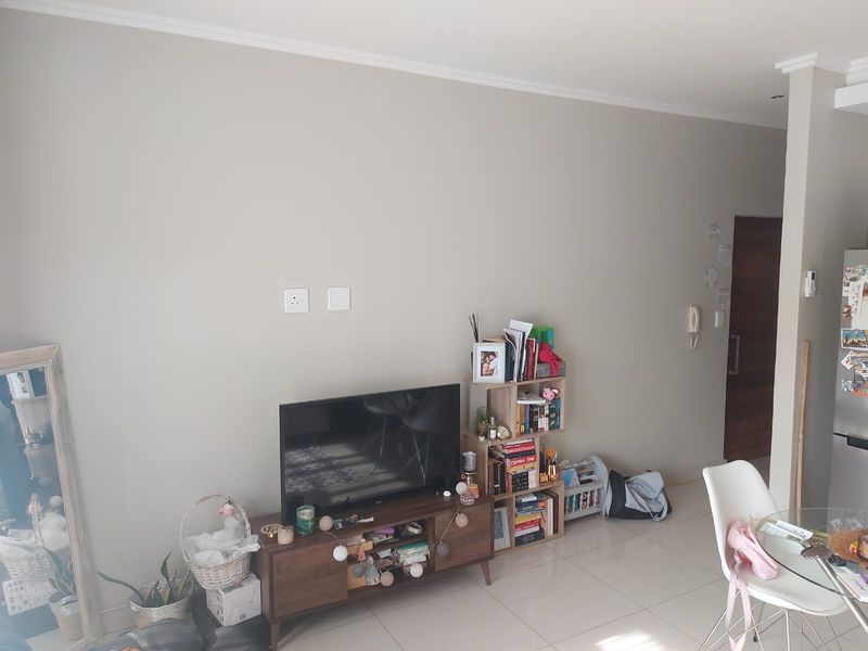 A bright living area featuring neutral walls, tiled flooring, and an integrated intercom system, providing a clean and functional space.