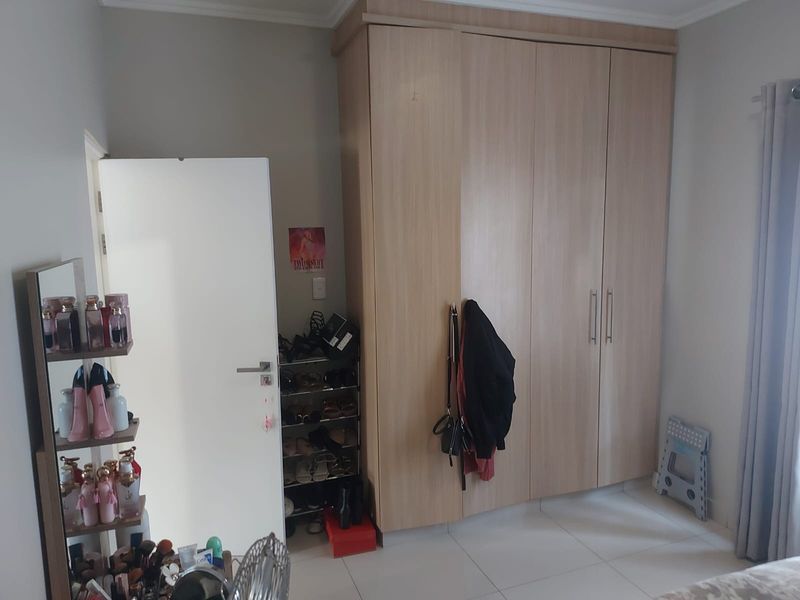 A bedroom featuring light wood-finish built-in wardrobes and neutral tiled flooring, providing ample storage space.
