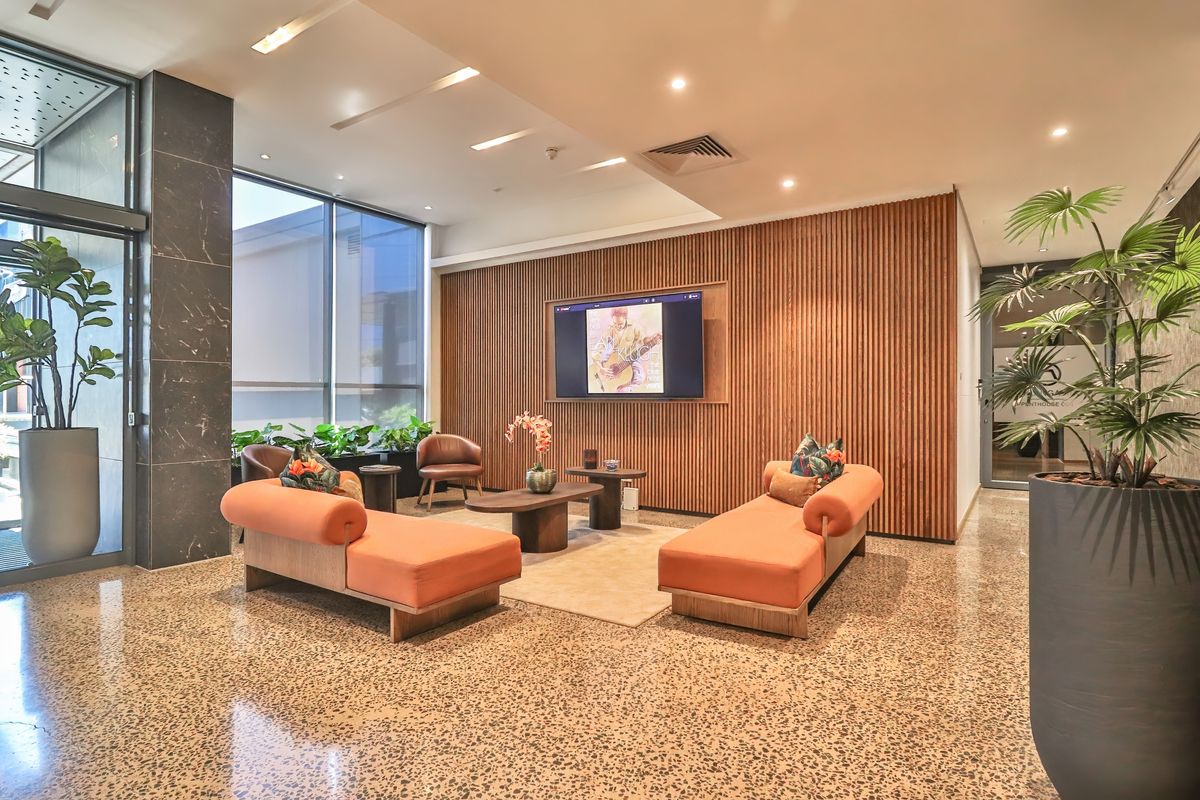 Modern lobby or lounge area featuring polished terrazzo flooring, elegant timber slat wall paneling, and floor-to-ceiling windows providing ample natural light.