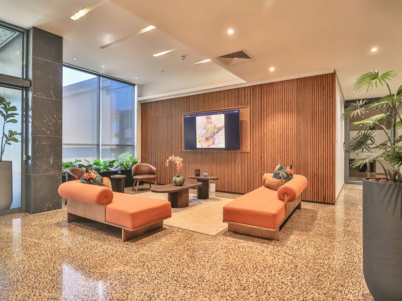 Modern lobby or lounge area featuring polished terrazzo flooring, elegant timber slat wall paneling, and floor-to-ceiling windows providing ample natural light.