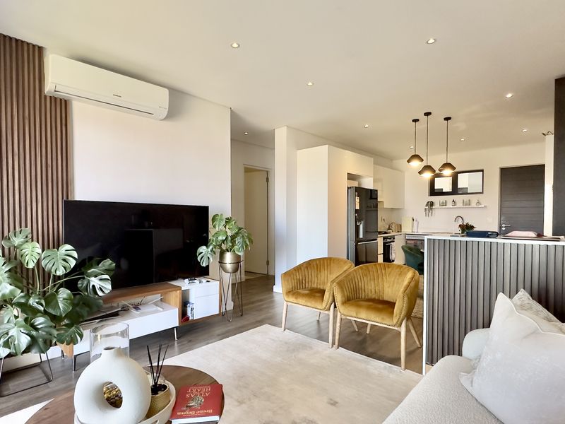 Modern open-plan living area featuring timber slat wall detailing, recessed lighting, and a seamless transition to a contemporary kitchen with an island.
