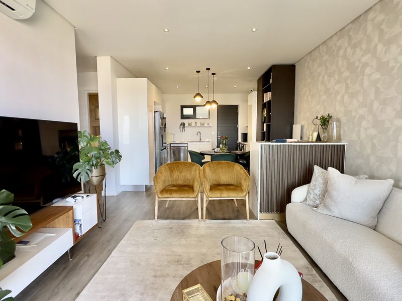 Modern open-plan living and kitchen area featuring laminate flooring, recessed lighting, a split-system air conditioner, and contemporary kitchen cabinetry.