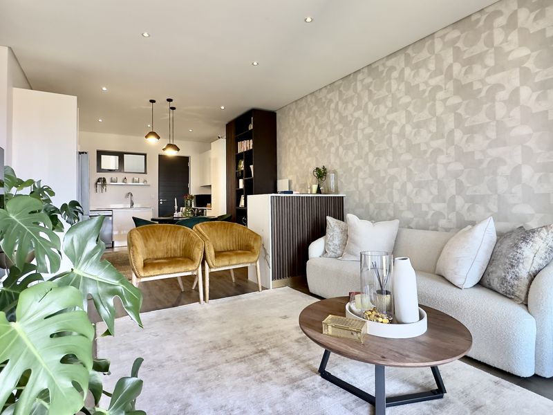Modern open-plan living area featuring a contemporary kitchen, recessed lighting, and stylish patterned wallpaper, creating a cohesive and inviting space.