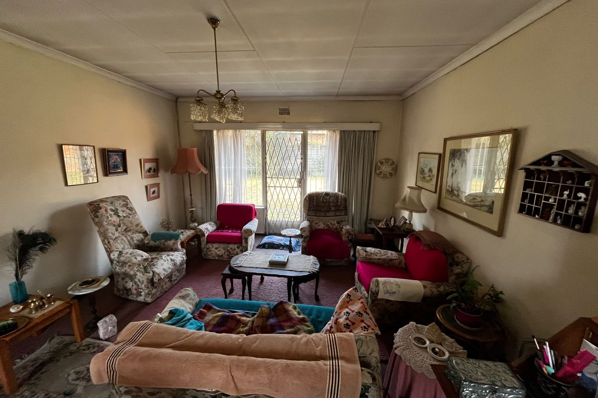 A dated living room featuring a chandelier, carpet flooring, and a security gate leading to the exterior.