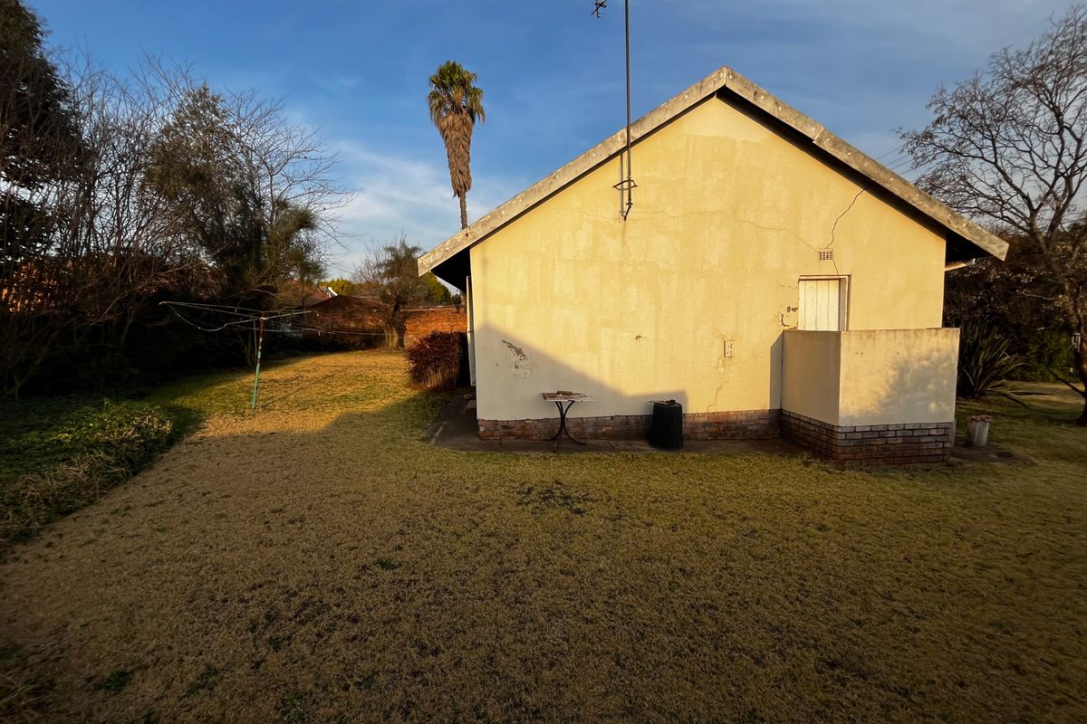 Rear view of the house showing the exterior wall, concrete patio area, and surrounding garden space.