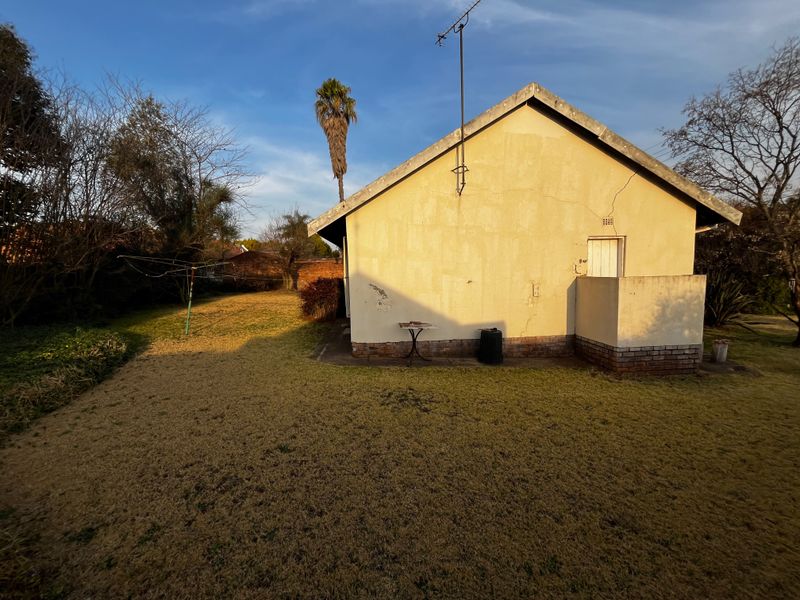 Rear view of the house showing the exterior wall, concrete patio area, and surrounding garden space.