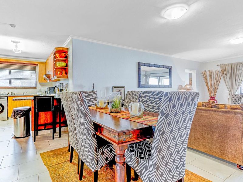 Open-plan living and dining area featuring tiled flooring and an integrated kitchen with wooden cabinetry.