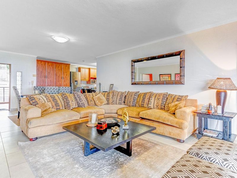 Open plan living area featuring tiled flooring and a connected kitchen with wooden cabinetry, providing a functional and spacious layout.