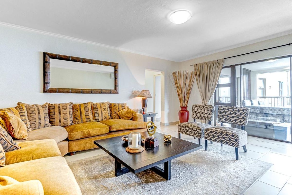 A bright and spacious living room featuring tiled flooring and a large sliding glass door providing access to the balcony.