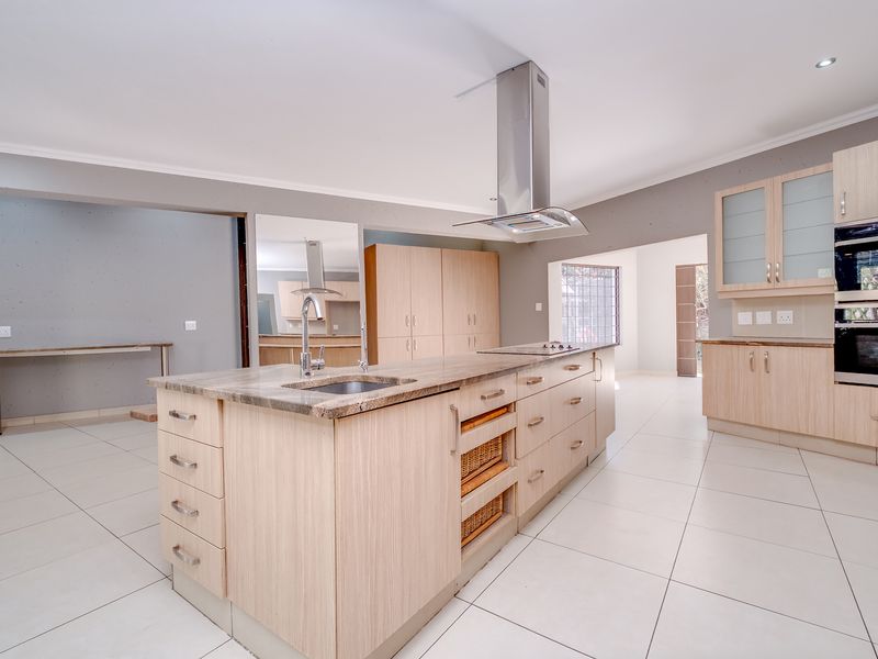 Spacious modern kitchen featuring a large central island with stone countertops, built-in appliances, and light wood cabinetry throughout.
