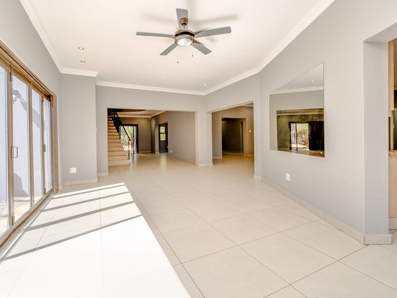 Spacious open-plan living area featuring neutral tiled flooring, recessed lighting, a ceiling fan, and large sliding glass doors leading to the exterior.