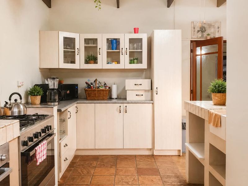 A rustic kitchen featuring exposed timber beams, tiled flooring, built-in cabinetry, and a gas stove with an oven.