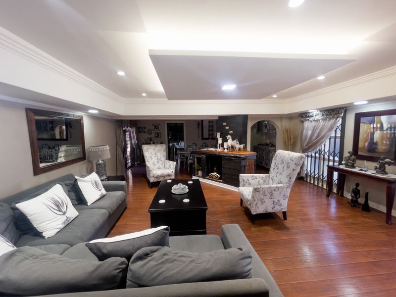 Spacious living room featuring hardwood flooring, a distinctive recessed ceiling with integrated lighting, and a central fireplace feature.