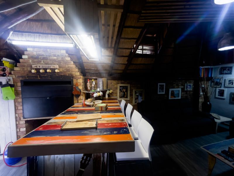 A rustic living area featuring a thatched roof, exposed brick fireplace, and a built-in bar counter, creating a cozy and unique entertainment space.