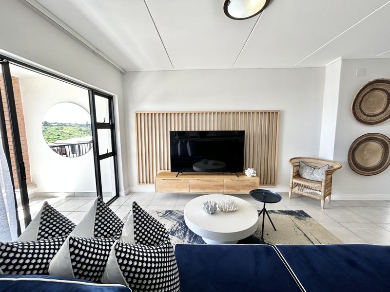 A bright and modern living room featuring a stylish slatted timber feature wall, floating media console, and large sliding glass doors leading to a balcony.