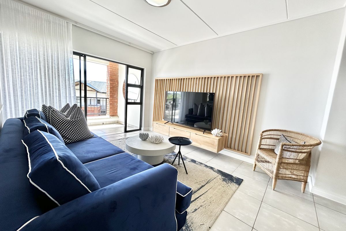 A bright and modern living room featuring a stylish slatted timber feature wall, floating media console, and direct access to a private balcony.