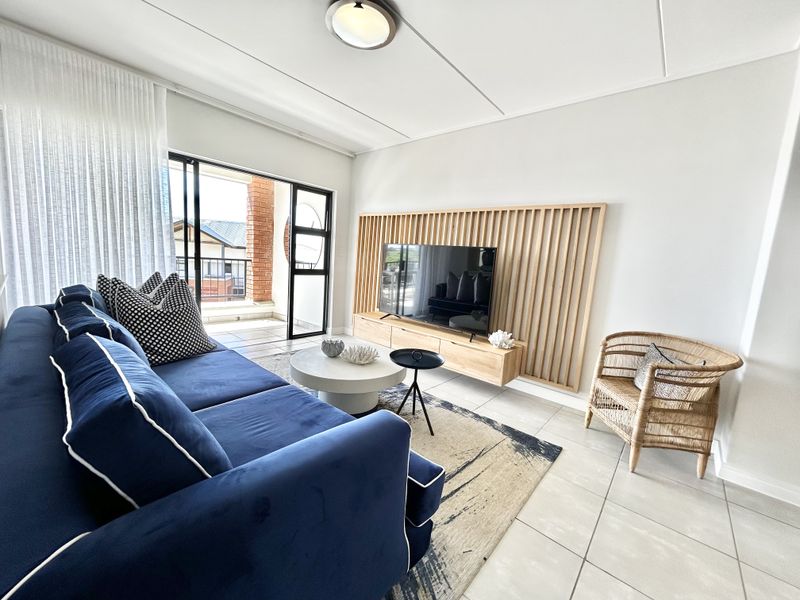 A bright and modern living room featuring a stylish slatted timber feature wall, floating media console, and direct access to a private balcony.