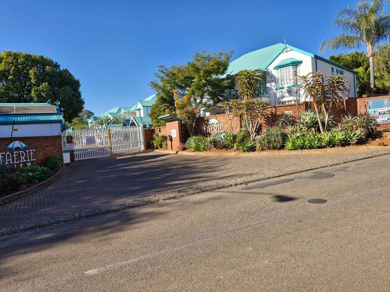 Front entrance view of the Faerie View apartment complex, featuring a secure gated access point, brick boundary walls, and established landscaping.