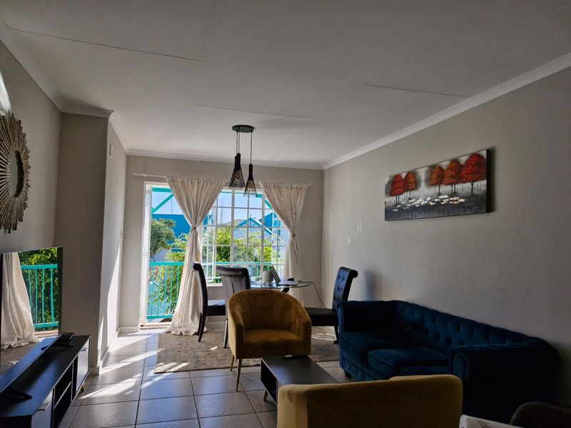 A bright living room featuring tiled flooring, coved ceilings, and a sliding glass door that provides access to an outdoor balcony area.