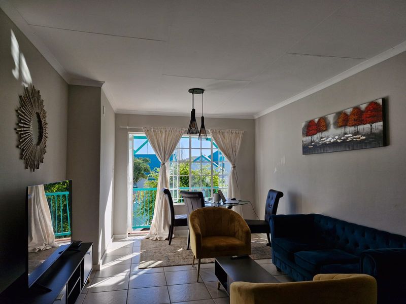 A bright living room featuring tiled flooring, coved ceilings, and a sliding glass door providing access to an outdoor balcony area.