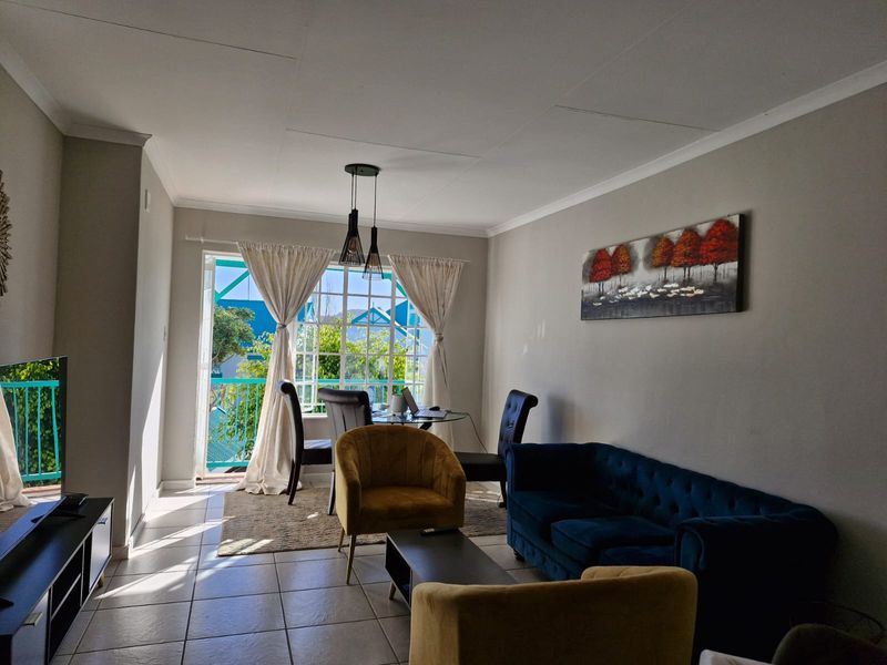 A bright living room featuring tiled flooring and a sliding glass door that provides access to an outdoor balcony area.