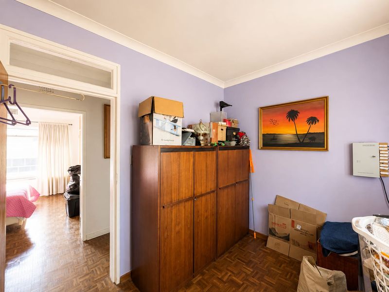 A bedroom featuring parquet flooring and a coved ceiling, with a doorway leading to an adjacent room.