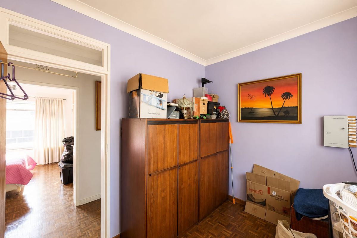 A bedroom featuring parquet flooring and a coved ceiling, with a doorway leading to an adjacent room.