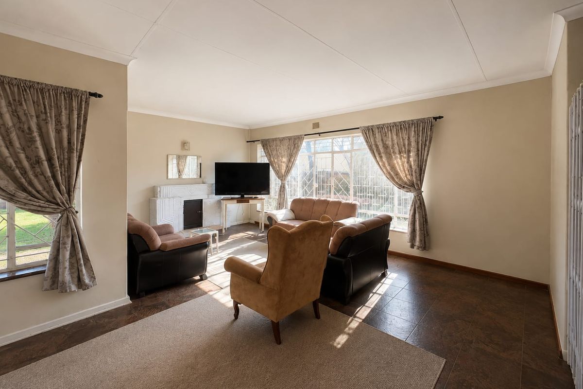 Spacious living room featuring tiled flooring, a fireplace, and large windows that provide ample natural light.