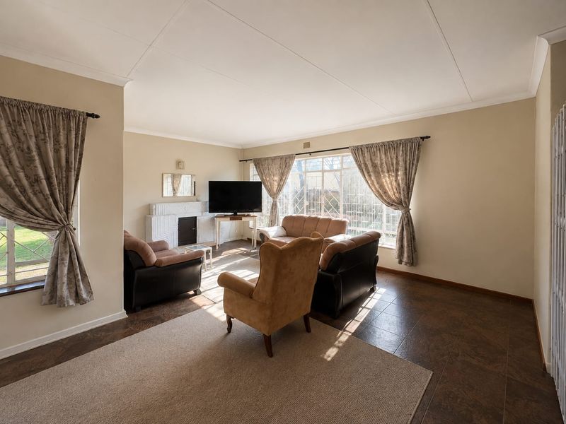 Spacious living room featuring tiled flooring, a fireplace, and large windows that provide ample natural light.