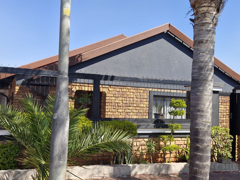 Front elevation of a residential property featuring a brick facade, tiled roof, and secure perimeter fencing with spiked security topping.