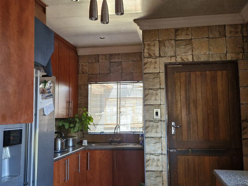 A functional kitchen featuring wood-finish cabinetry, stone-textured wall tiles, and laminate countertops, offering a traditional aesthetic with potential for modern updates.