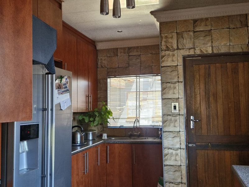 A functional kitchen featuring wood-toned cabinetry, stone-textured wall accents, and a classic timber door, offering a traditional aesthetic with potential for modern updates.