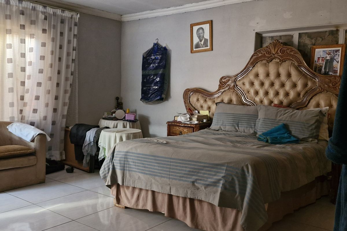 A spacious bedroom featuring tiled flooring and classic cornicing, offering a neutral base for personalization.