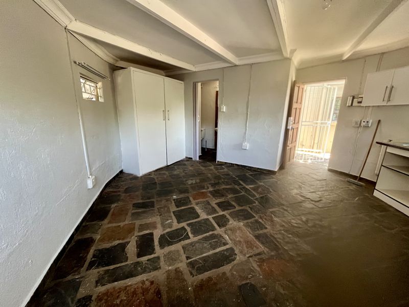 Open plan living area featuring rustic stone flooring, exposed ceiling beams, built-in storage, and direct access to an exterior security gate.