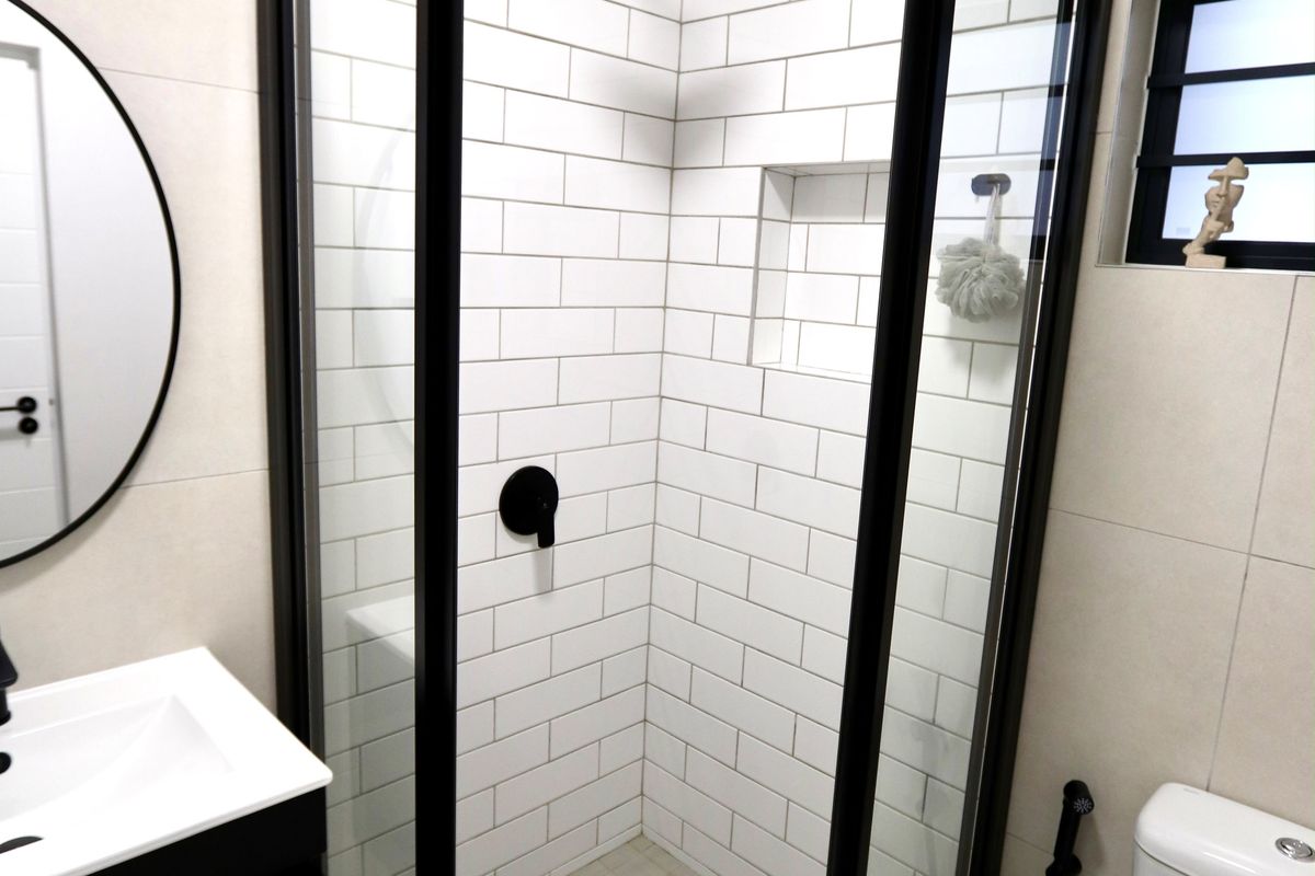 Modern bathroom featuring a corner shower enclosure with black framing, subway tile backsplash, wall-mounted vanity, and contemporary fixtures.