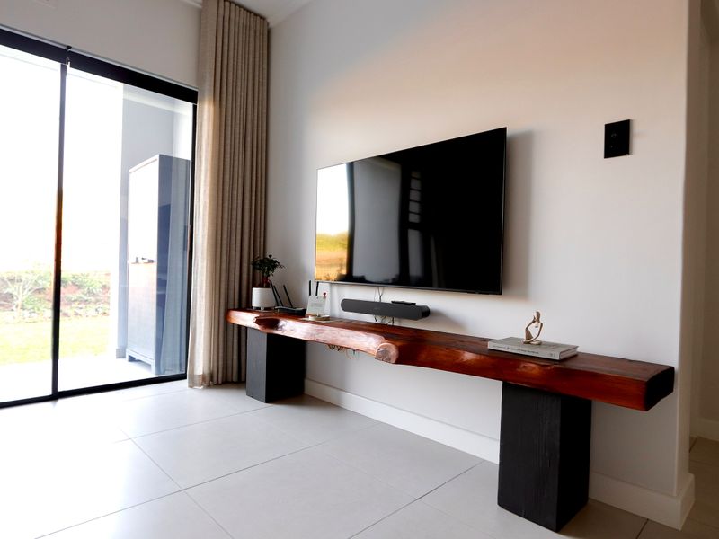 Modern living room featuring large sliding glass doors providing natural light and access to the outdoor area, complemented by neutral tiled flooring.