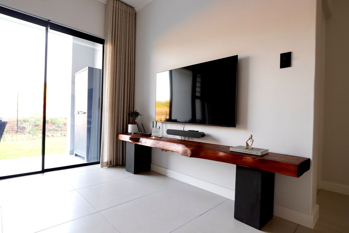 Modern living room featuring large sliding glass doors providing natural light and access to the outdoor area, complemented by neutral tiled flooring.