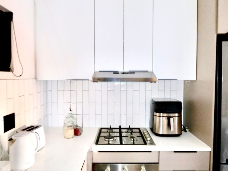 Modern kitchen featuring white cabinetry, subway tile backsplash, quartz countertops, and integrated stainless steel gas hob and oven appliances.