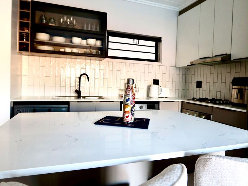 Modern kitchen featuring white quartz countertops, subway tile backsplash, sleek cabinetry, and integrated appliances, offering a clean and functional culinary space.